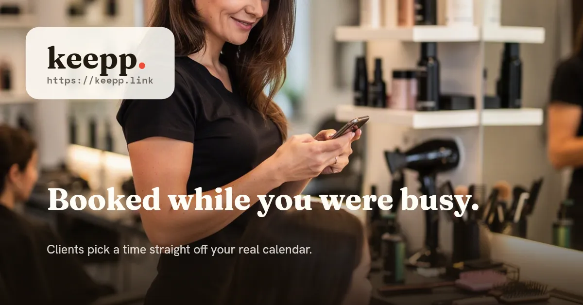 A hairstylist glancing at her phone between appointments while a client waits in the salon chair